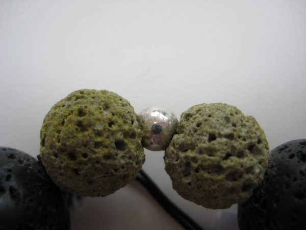 Das Armband aus Lavastein in der Nahaufnahme - man sieht zwei grüne Steine.