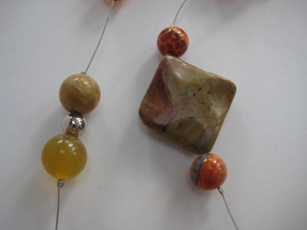 Zoom auf die einzelnen Steine einer zierlichen Edelsteinkette aus Achat, Karneol und Jaspis in Brauntönen. Zu sehen sind Quadrate aus Achat, Jaspis und Karneolkugeln.