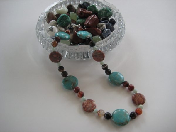 Farbenprächtige Edelsteinkette aus Achat, Tuerkis, und Amazonit aus einer Glasschale fließend