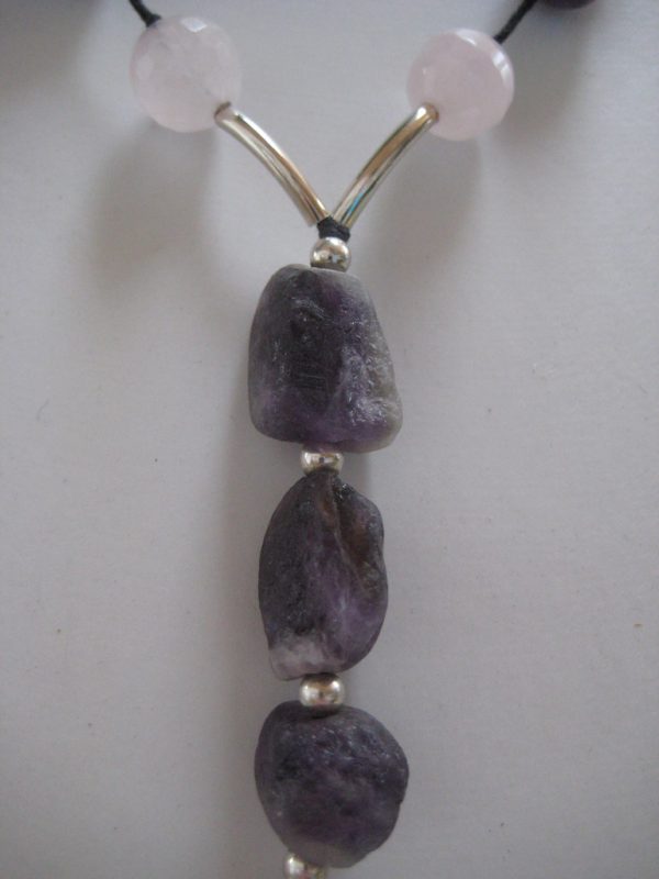 Zoom auf den langen Anhänger aus violetten Amethysten und die silbernen Zwischenstücke einer Edelsteinkette aus Amethyst, Bergkristall und Rosenquarz.