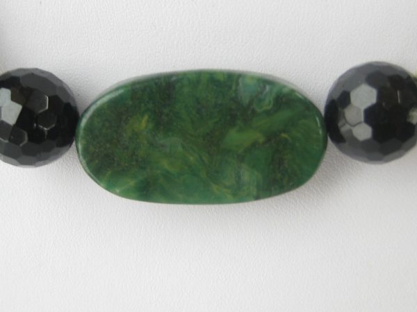 Zoom auf den grünen ovalen Jadestein einer Edelsteinkette aus Jade, Serpentin und Turmalin.