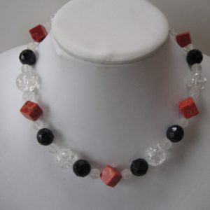Edelsteinkette aus Koralle, Bergkristall und Blaufluss in den Farben Rot, klar weiß und dunkelblau auf einer weißen Damenbüste.