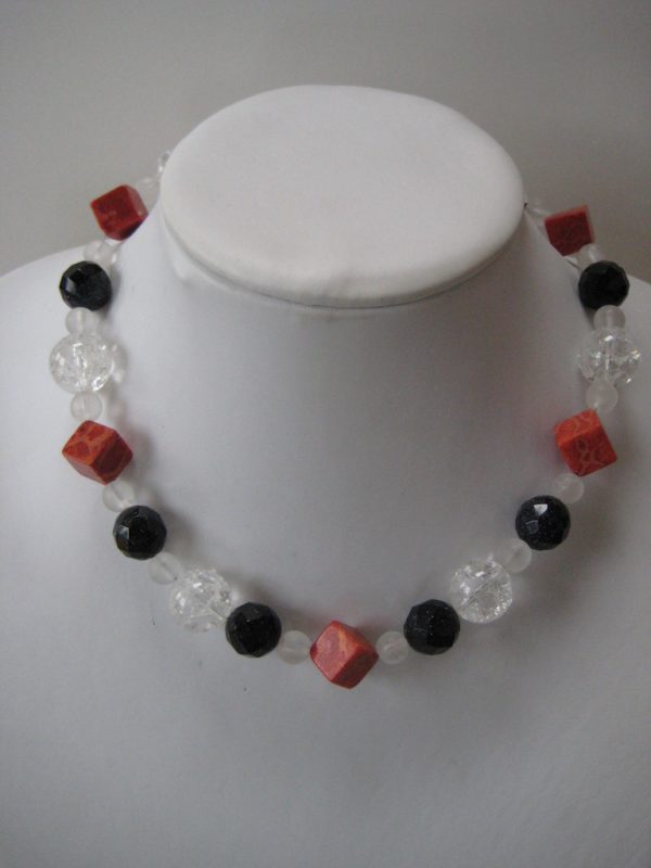 Edelsteinkette aus Koralle, Bergkristall und Blaufluss in den Farben Rot, klar weiß und dunkelblau auf einer weißen Damenbüste.