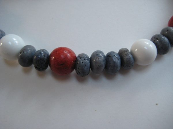 Nahaufnahme von einzelnen Steinen einer Edelsteinkette aus Koralle und Jade mit roten, blauen und weißen Edelsteinen.