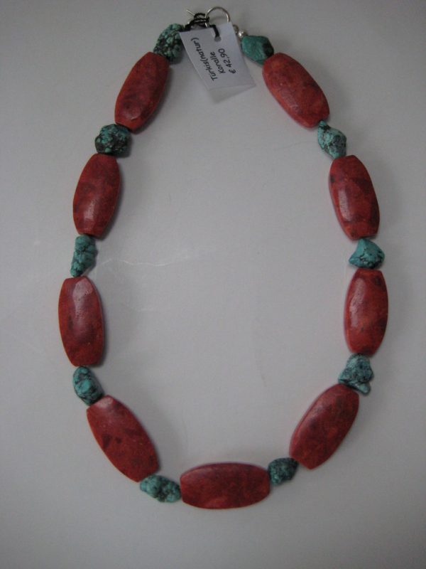 Aufgelegte Edelsteinkette aus Koralle und Türkis. Zu sehen sind rote, ovale Korallen und kleinere Türkisnuggets.