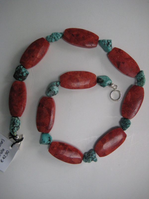 Zu einer Schnecke aufgelegte Edelsteinkette aus Koralle und Türkis. Zu sehen sind rote, ovale Korallen und kleinere Türkisnuggets.