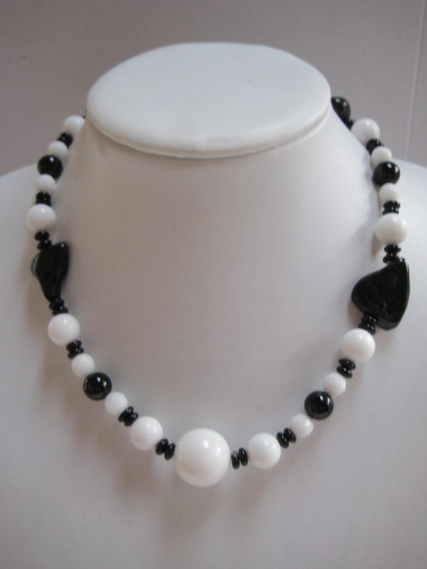 Eine Edelsteinkette aus Onyx und Jade auf einer weißen Damebüste.