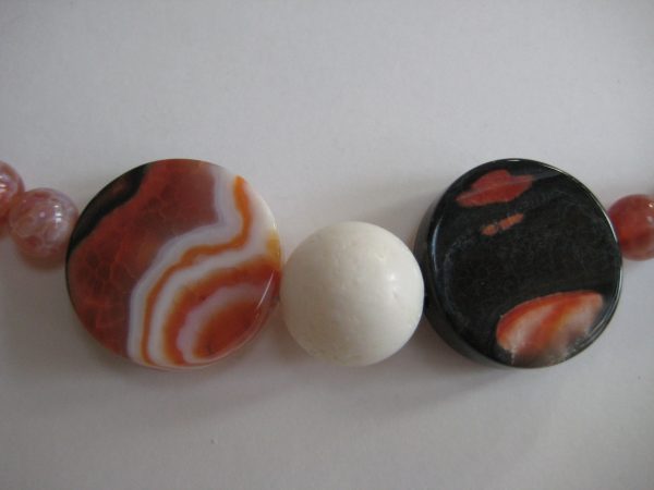Zoom auf die großen schwarz-orangen Steine einer Edelsteinkette aus Onyx, Karneol und Koralle.