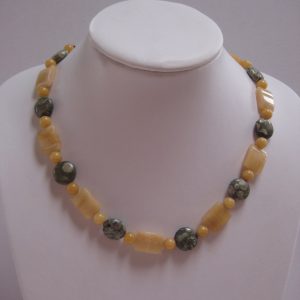 Gelb-Graue Edelsteinkette aus Rhyolith, Jade und Aragonit auf einer weißen Damenbüste.