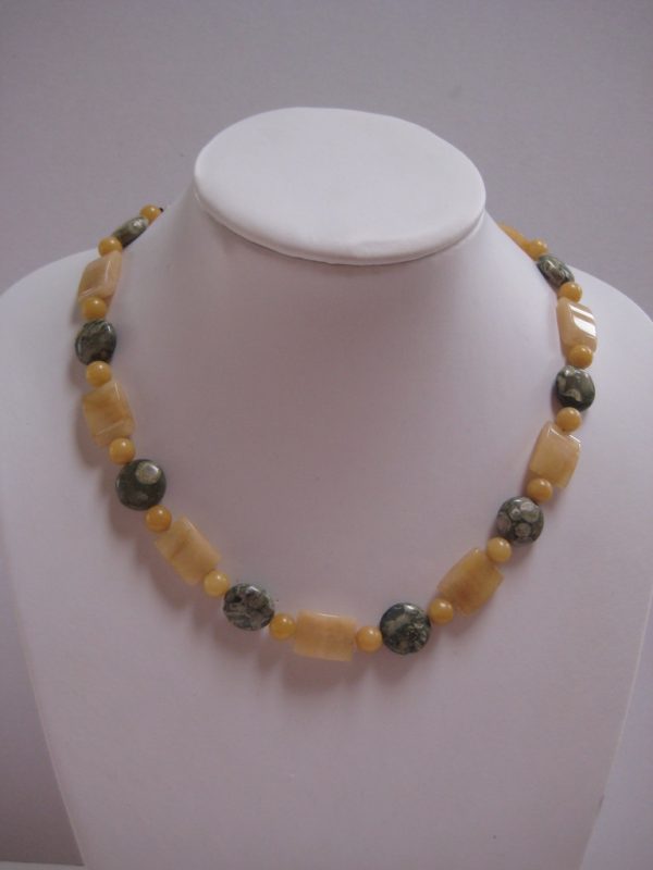 Gelb-Graue Edelsteinkette aus Rhyolith, Jade und Aragonit auf einer weißen Damenbüste.