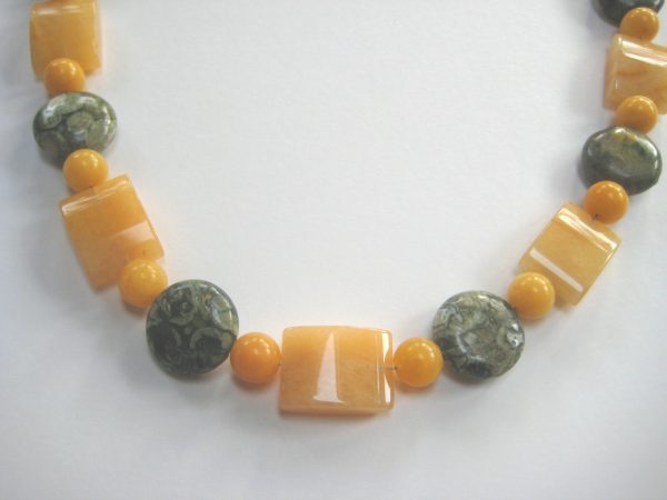 Fokus auf einzelne Perlen der gelb-grauen Edelsteinkette aus Rhyolith, Jade und Aragonit.