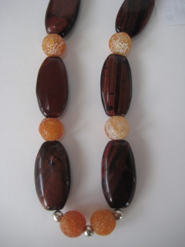 Zoom auf die braunen Tigerauge-Ellipsen einer Edelsteinkette aus Tigerauge und Karneol in schimmernden Brauntönen.