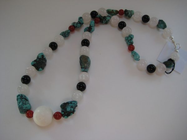 Aufgelegte Edelsteinkette aus Türkis, Rosenquarz, Karneol, und Onyx. Die Steine sind weiß, schwarz, rot, und türkis.