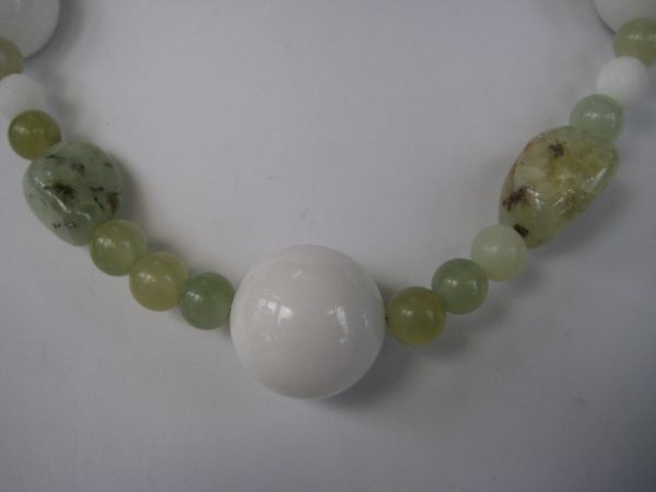 Zoom auf den weißen Jadeanhänger einer Edelsteinkette aus Jade, Prehnit und Serpentin in frühlingsfrischen grünen Farben.