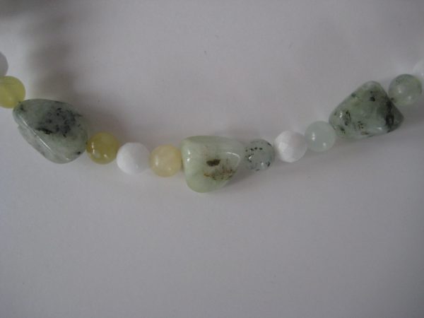 Zoom auf die einzelnen Steine einer Edelsteinkette aus Jade, Prehnit und Serpentin in frühlingsfrischen grünen Farben.