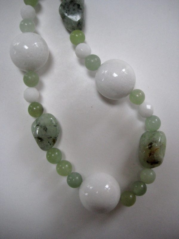 Zoom auf einzelnen Steine einer Edelsteinkette aus Jade, Prehnit und Serpentin in frühlingsfrischen grünen Farben.